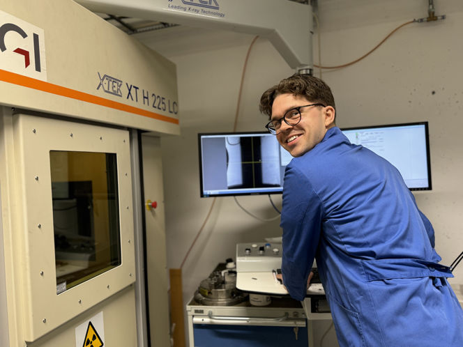 Fredrik wearing a blue lab coat. In the background you can see typical lab equipment.